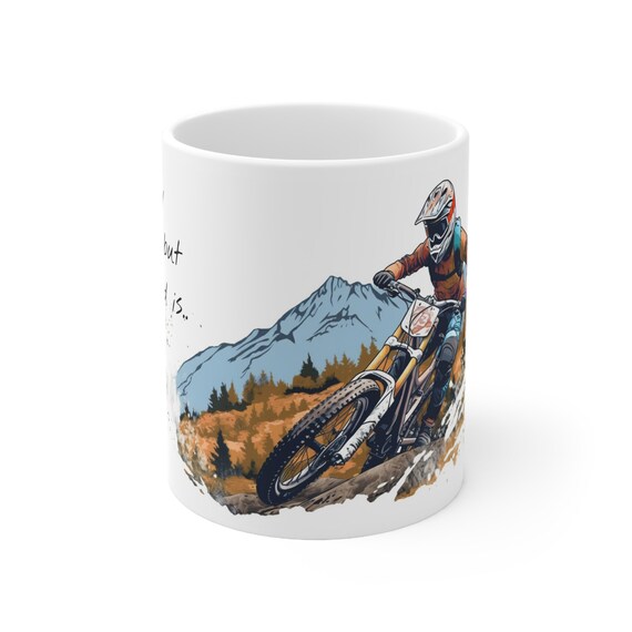 White mug printed with a mountain biker riding in front of blue mountains
